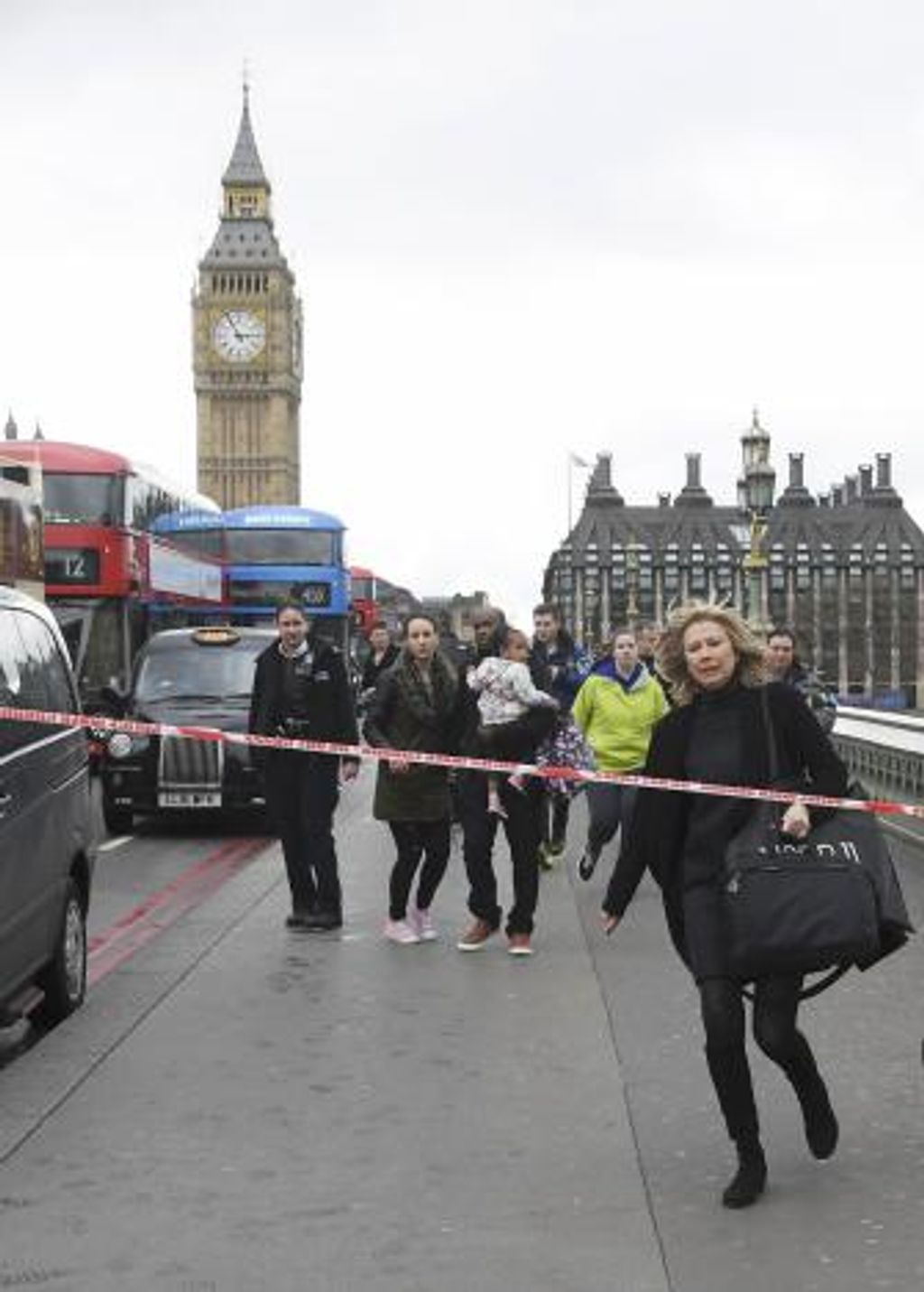 A woman ducks under a police tape after an incident on Westminster Bridge in London
