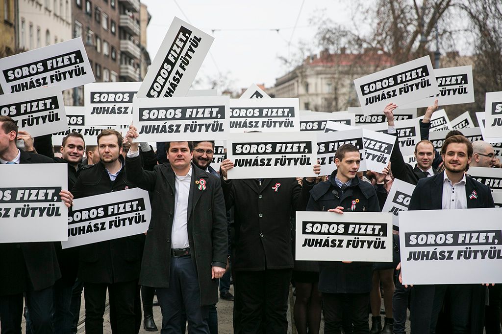 Résztvevők "Soros fizet/Juhász fütyül" feliratú transzparensekkel a Fidelitas demonstrációján az 1848-49-es forradalom és szabadságharc 169. évfordulója alkalmából rendezett állami ünnepség előtt a Magyar Nemzeti Múzeumnál Fotó: Horváth Péter Gyula