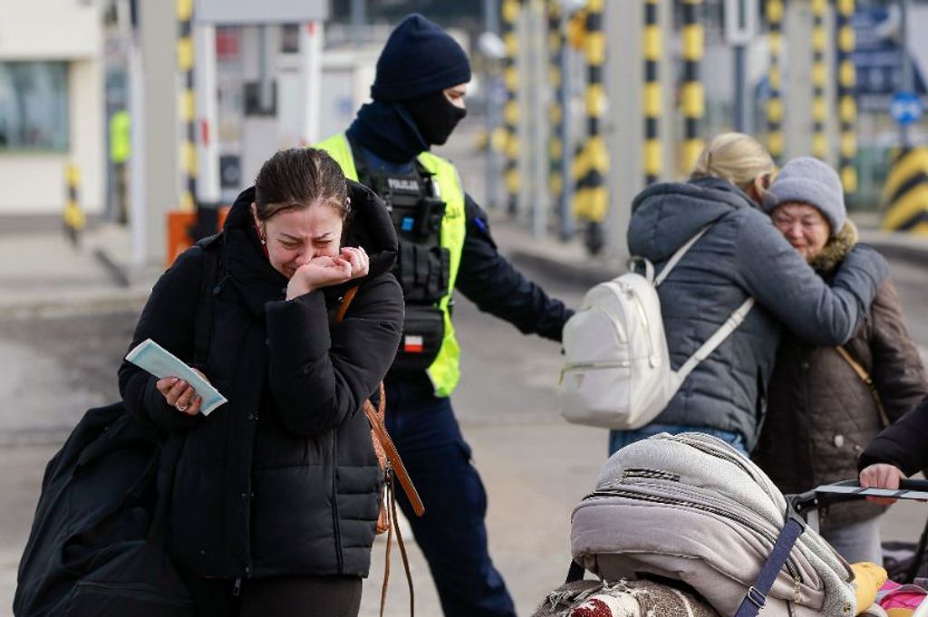 Ukrajnából menekülő emberek sírnak, miközben családtagjaikkal találkoznak a lengyel-ukrán határon, a délkelet-lengyelországi Medykában