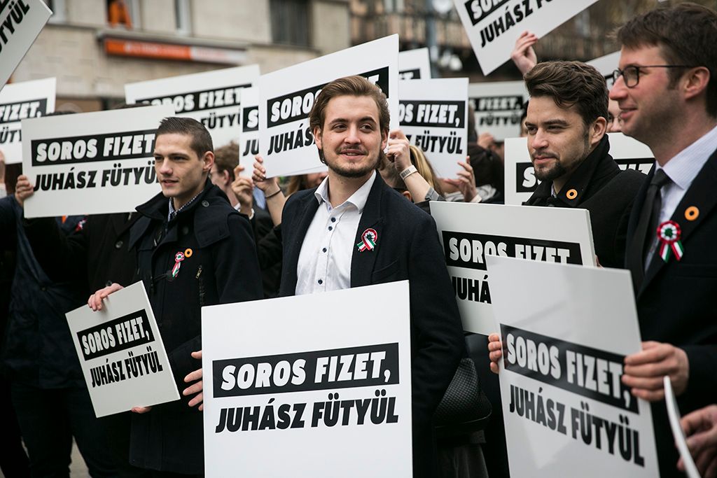 Résztvevők "Soros fizet/Juhász fütyül" feliratú transzparensekkel a Fidelitas demonstrációján az 1848-49-es forradalom és szabadságharc 169. évfordulója alkalmából rendezett állami ünnepség előtt a Magyar Nemzeti Múzeumnál Fotó: Horváth Péter Gyula