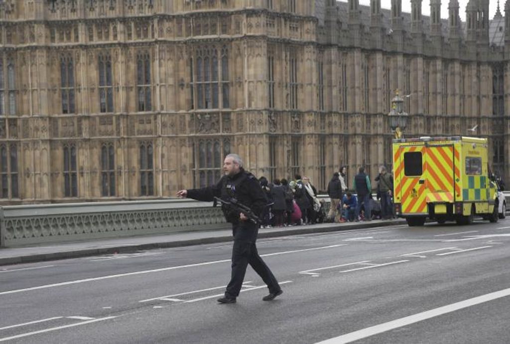 An armed police officer runs accross the road during an incident on Westminster Bridge in London