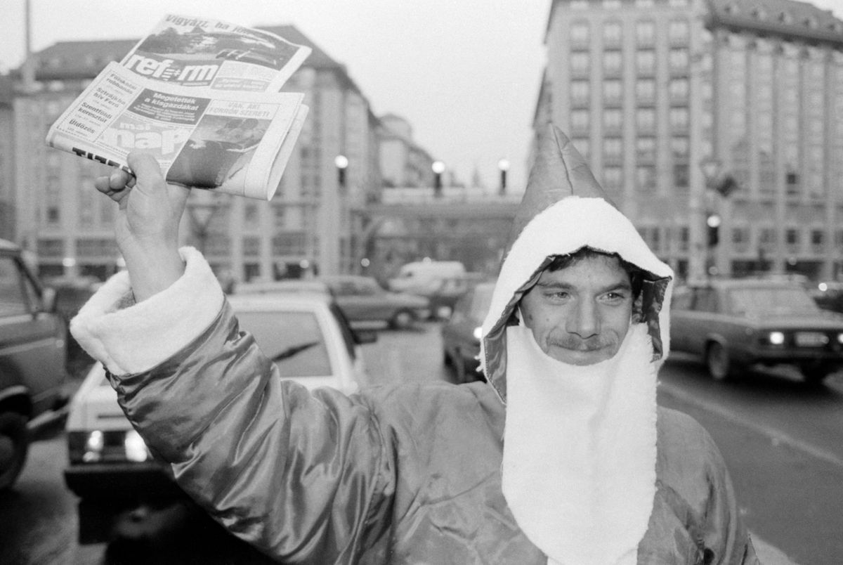 Budapest, 1990. december 5. Utcai újságárus Télapó jelmezben árulja a lapokat az autósoknak a Kálvin téri keresztezõdésben / MTI Fotó: Kleb Attila