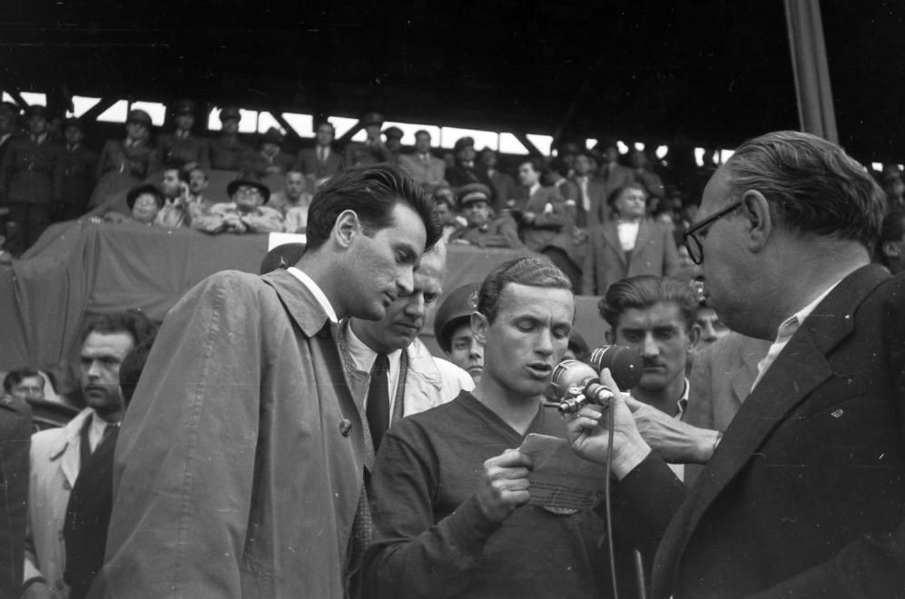Lakat Károly a mérkőzés előtt felolvas egy nyilatkozatot(?) a mikrofonba, mellette balra Szepesi György riporter, közöttük félig takarva Gulyás Gyula riporter, 1949 / Fotó: Fortepan.hu