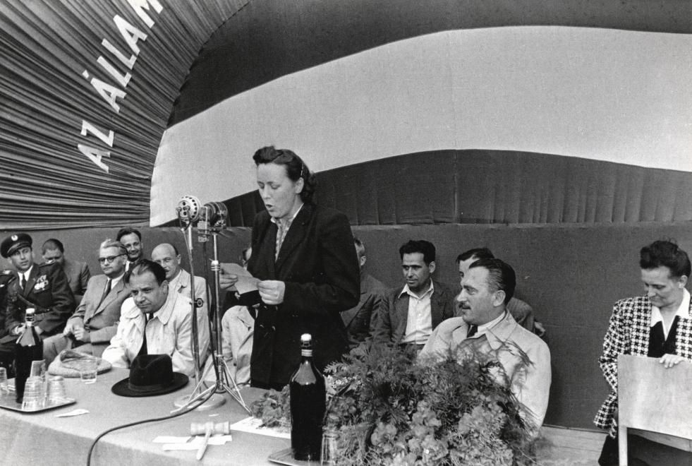 Kép az ÁVH-ról. Átadják az ÁVH csapatzászlóját (1949), szónokol a zászlóanya Farkas Mihályné (született Käthe Rüdiger) mellette balra Farkas Mihály, mögötte szemüveggel Zöld Sándor, félig takarva Donáth Ferenc. Jobbra a virágcsokor mögött Péter Gábor / Fotó: Fortepan.hu