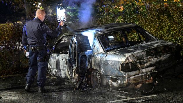 A police officer checks a burned out car at Karleksvagen in Burlov, near Malmo, Sweden, Tuesday Sept. 20, 2016. Police in Malmo say a recent surge in car fires, with about 30 cars set ablaze since Friday, could be linked to a crackdown on gangland crime, after police arrested three men with suspected links to organised crime involving guns and explosives. (Johan Nilsson / TT via AP)