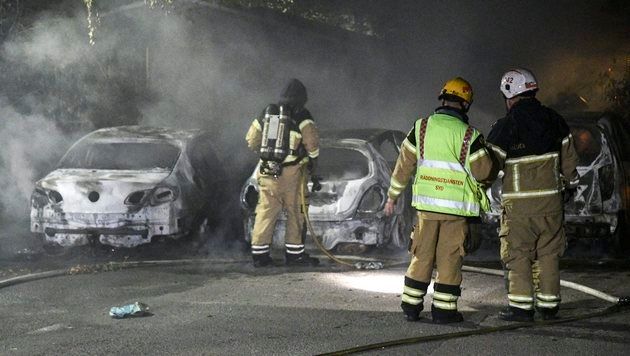 epa05489152 Swedish firemen stand next to extinguished car that were set on fire, in Malmo, Sweden, close to midnight on 15 August 2016. Media reports state that Swedish police is investigating a series of vehicle burnings in various Malmo neighborhoods but was so far unable to get hold of any perpetrators. EPA/JOHAN NILSSON SWEDEN OUT