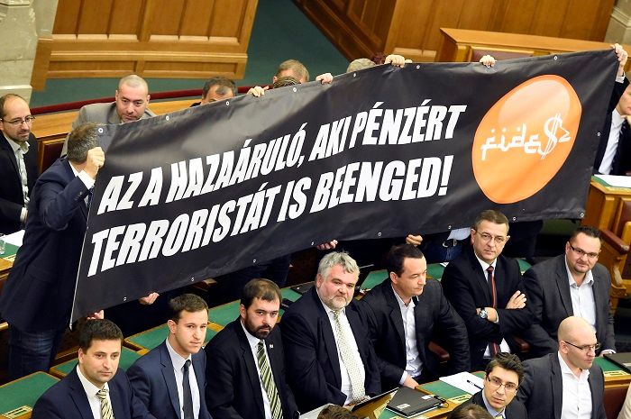 Budapest, 2016. november 8. Jobbikos képviselõk Az a hazaáruló, aki pénzért terroristát is beenged! feliratú molinót tartanak az alaptörvény hetedik módosításáról szóló szavazás alatt az Országgyûlés plenáris ülésén 2016. november 8-án. 131 képviselõ szavazott igennel, 3 nemmel, így nem kapta meg a kétharmados támogatást Orbán Viktor miniszterelnök alkotmánymódosítási javaslata, amely kimondta volna, hogy Magyarországra idegen népesség nem telepíthetõ be. MTI Fotó: Kovács Tamás