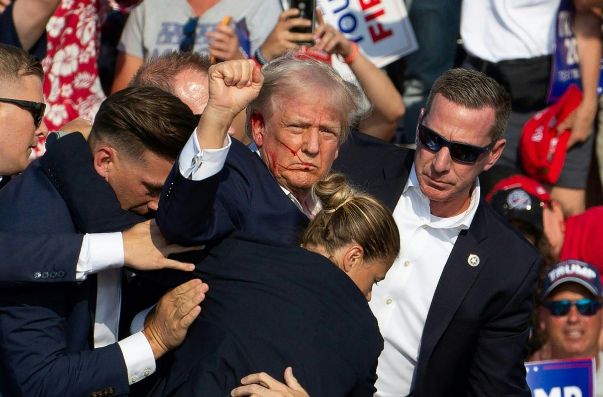 Donald Trump amerikai elnököt véres arccal vezetik le a színpadról a Secret Service emberei a Pennsylvania állambeli Butlerben, 2024. július 13-án ( AFP / Rebecca DROKE)