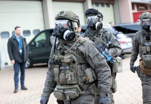 Angehörige des Spezialeinsatzkommandos der Polizei (SEK) begeben sich in Schutzanzügen zu einer eingerichteten Station z