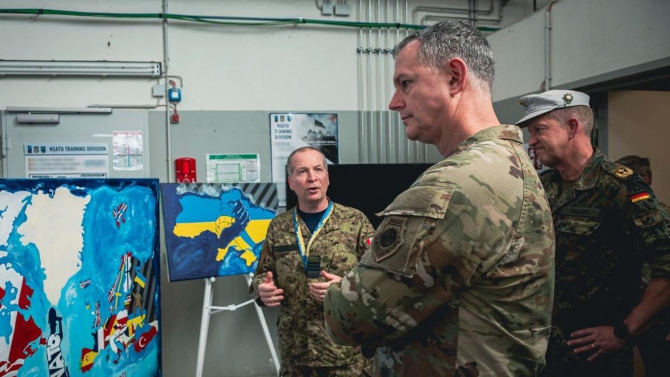 Alexus G. Grynkewich tábornok, a SACEUR parancsnoka, valamint Maik Keller vezérőrnagy, az NSATU helyettes parancsnoka rövid ismertetőt kap arról a műalkotás-sorozatról, amely a NATO Ukrajnának nyújtott támogatását hivatott megörökíteni. Fotó: NATO.